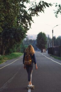 Mulher jovem andando de skate em rua urbana durante o dia, transmitindo leveza, disciplina, liberdade e estilo de vida ativo.