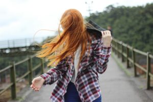 Retrato de uma mulher ruiva ao ar livre com o cabelo soprando ao vento.