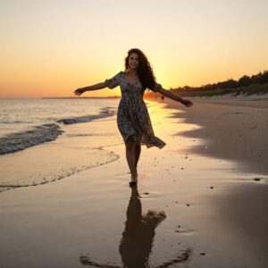 Mulher de braços abertos caminhando na praia, símbolo de liberdade, fé e recomeço com propósito. 