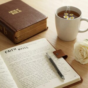 Caderno com reflexões espirituais e Bíblia, simbolizando os benefícios da rotina espiritual no dia a dia.